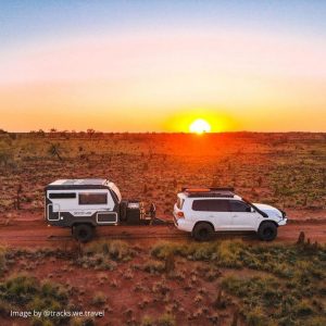 side view of a 4x4 and caravan in dessert with golden sunset background